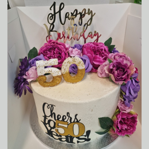 masked birthday mudcake with floral and happy birthday toppers
