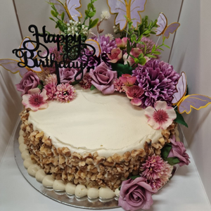 decorated carrot cake with flowers and happy birthday topper