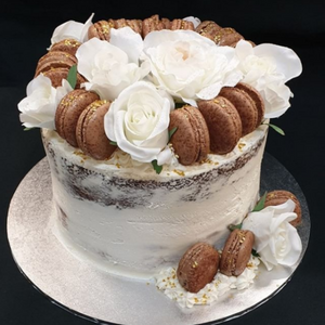 naked stacked cake topped with white roses and chocolate macarons