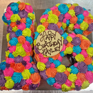 number cake piped with rainbow rosettes and a happy birthday chocolate plaque