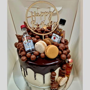 stacked mudcakes with chocolate drip topped with alcohol bottles and chocolates