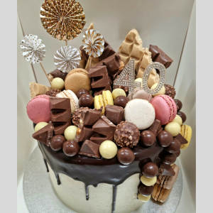 stacked mudcakes with chocolate drip topped with macarons and assorted chocolates