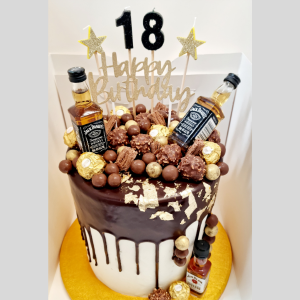 stacked mudcakes with a chocolate drip topped with chocolates, a birthday topper and mini alcohol bottles