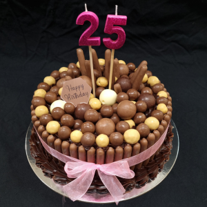 chocolate mudcake with chocolate ganache and topped with various chocolates with pink candles