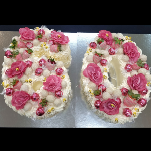 white chocolate number 60 cake topped with lindt chocolates, pink roses and white chocolates
